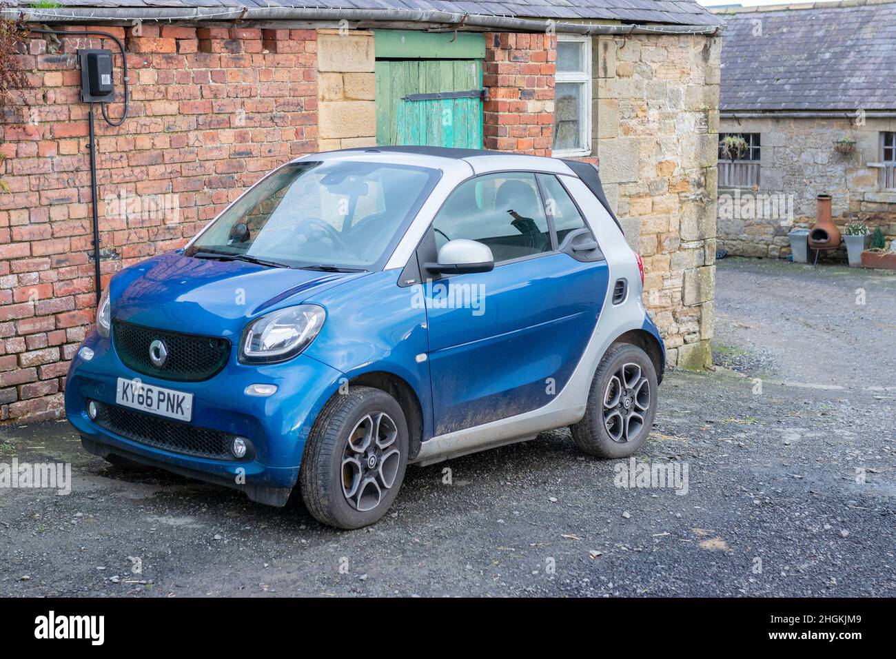 Softtop Blue Cabrio Smart Car fortwo vor rustikalen Bauernhäusern in Matfen Northumberland Stockfoto