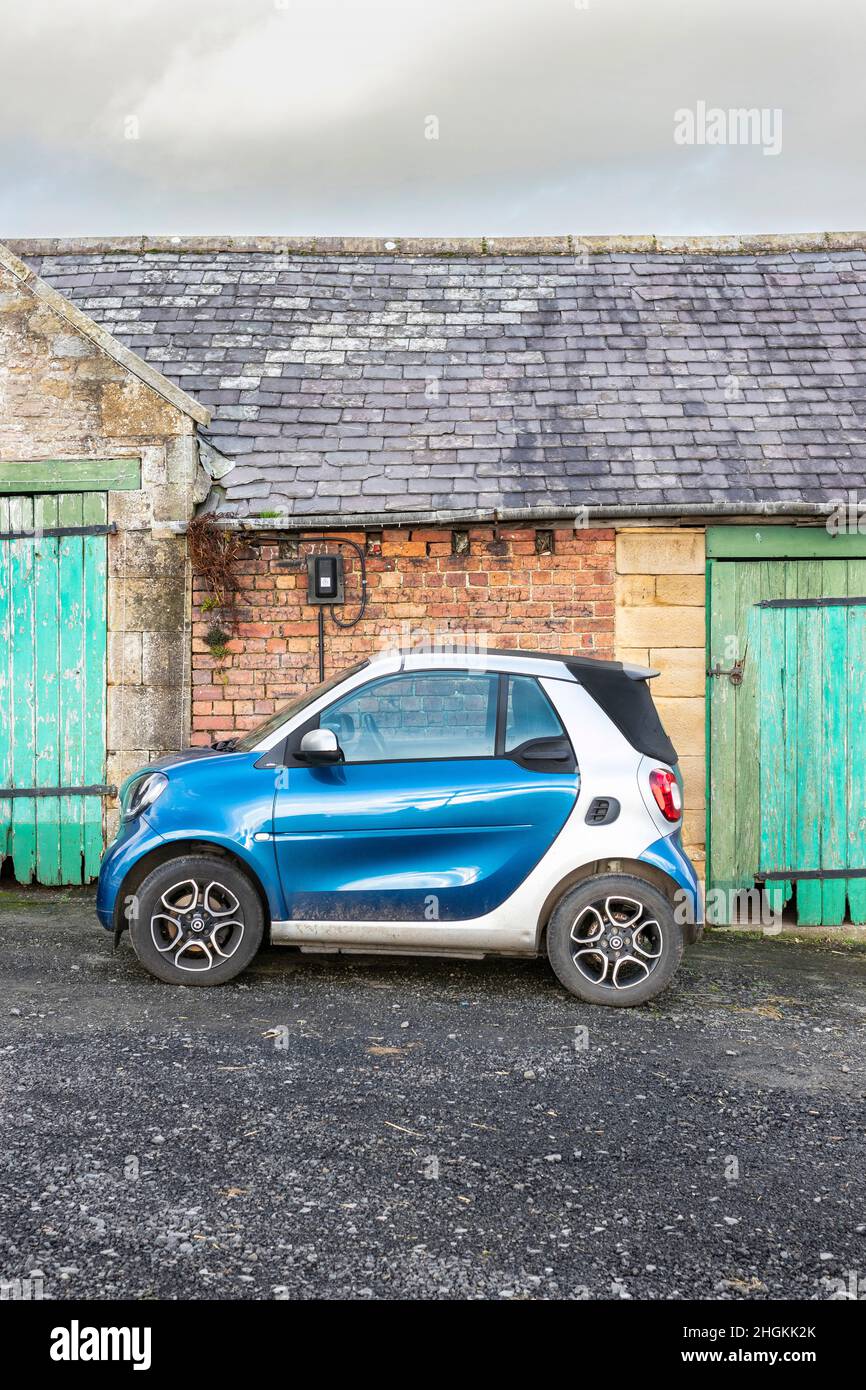 Seitenansicht des Soft TOP Blue Cabrio Smart Car fortwo vor rustikalen Bauernhäusern in Matfen Northumberland Stockfoto