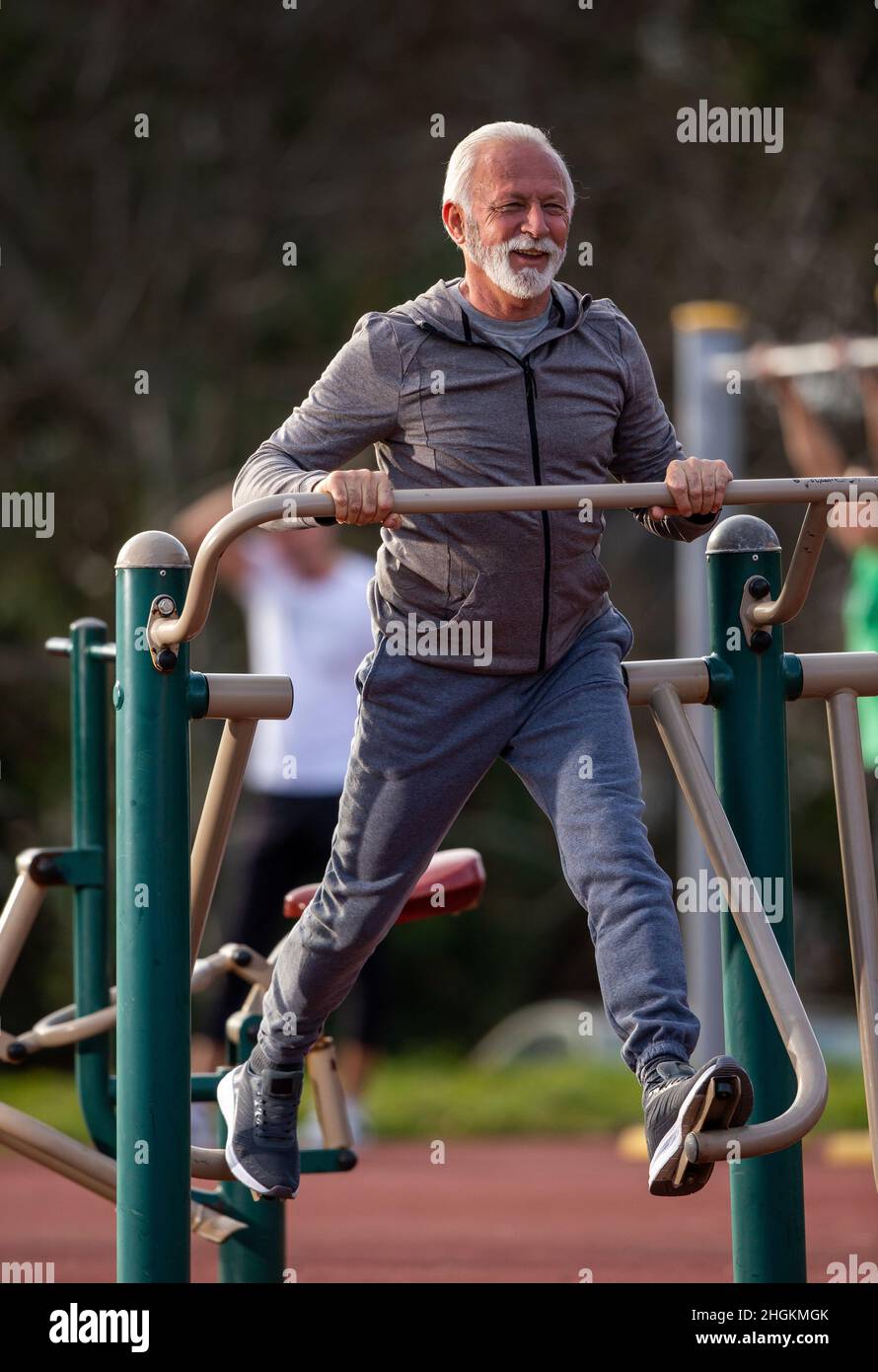 Senior Mann im Trainingsanzug auf Sky Stepper im öffentlichen Fitnessstudio im Freien trainieren Stockfoto