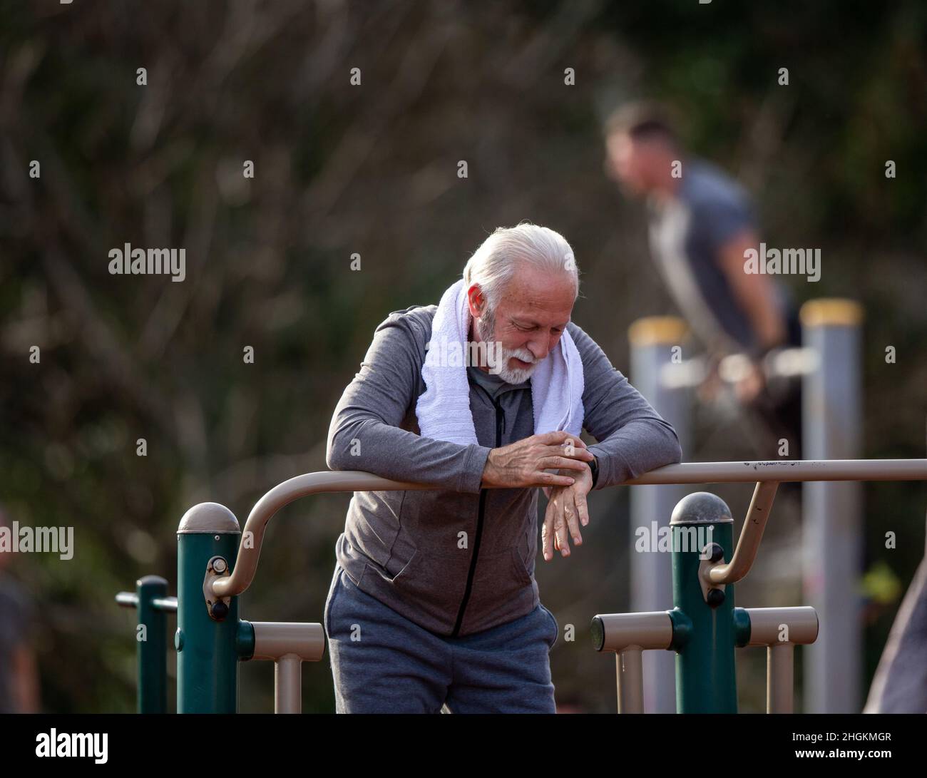 Seniorchef, der eine Smart Watch verwendet und die Ergebnisse nach dem Fitnesstraining im öffentlichen Fitnessstudio im Freien verfolgt Stockfoto