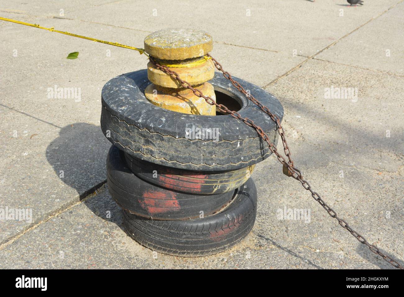 Alte Reifen Auf Bollard Mit Rostiger Kette Stockfoto