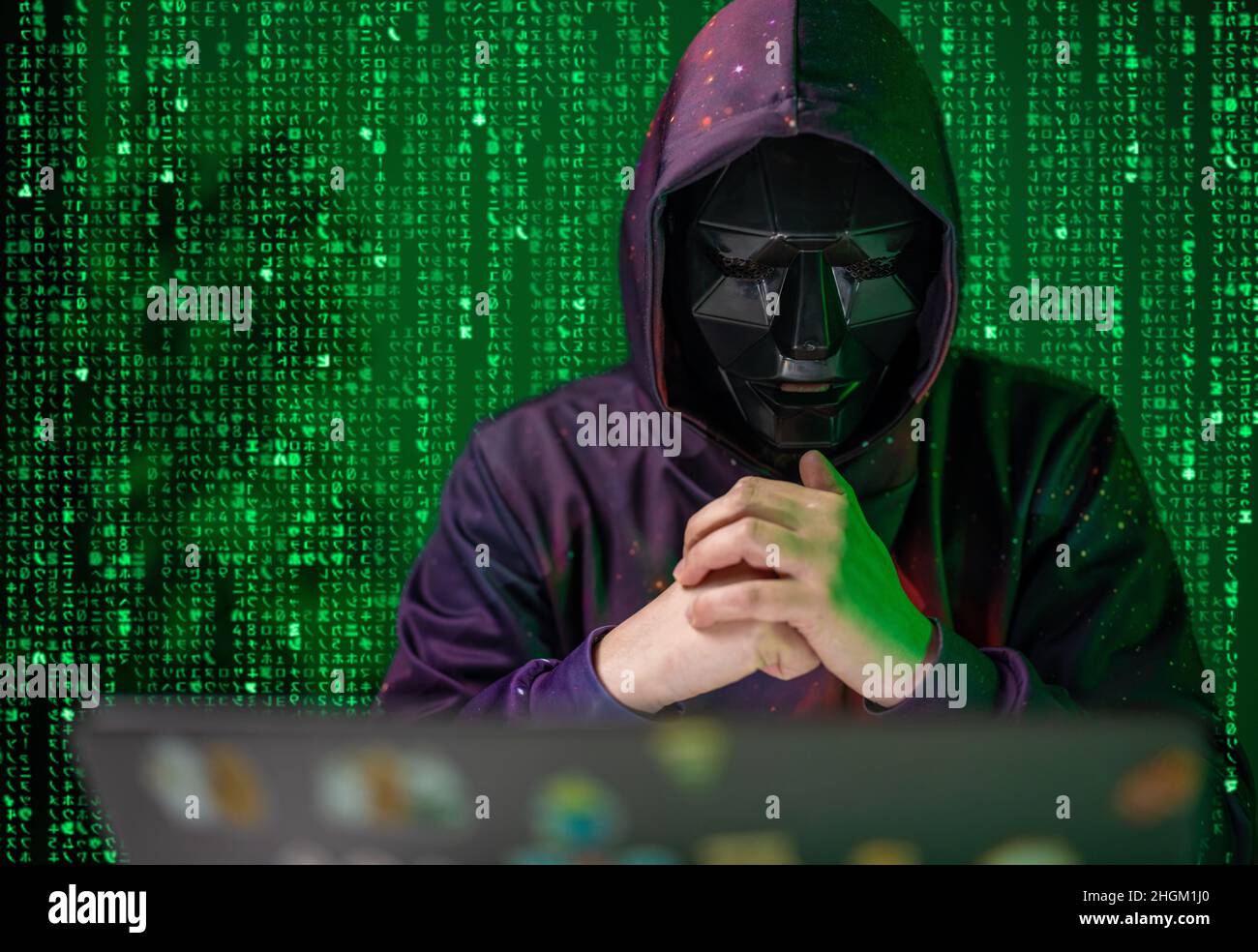 Hacker mit Laptop unter dem Matrixeffekt Stockfoto
