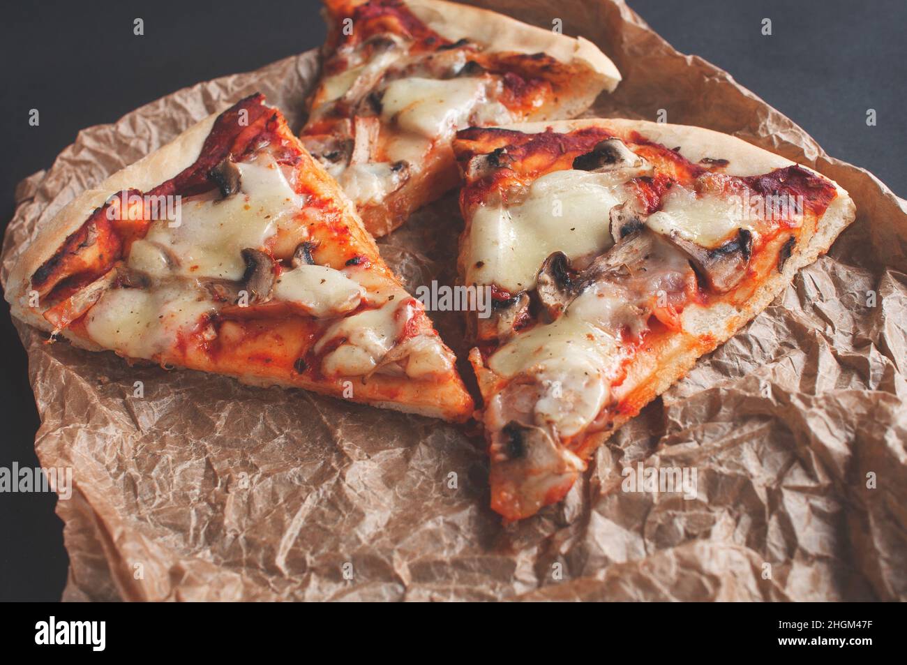 Scheiben frisch gebackene Pizza auf einer schwarzen Tafel auf dunklem Hintergrund Stockfoto