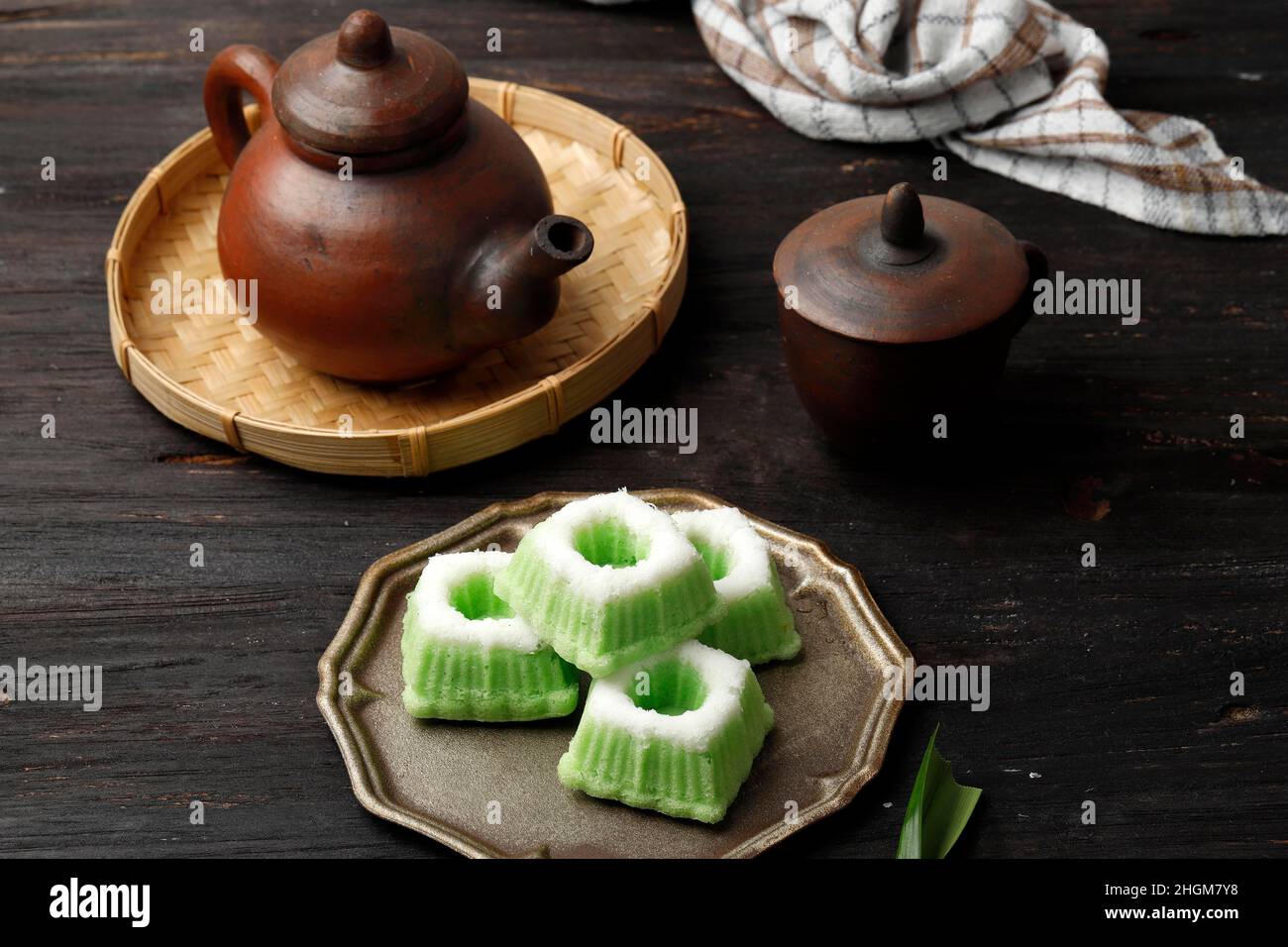 Kue Putu Ayu, indonesischer traditioneller Jajan-Pasar aus gedämpftem Mehl und geriebener Kokosnuss. Serviert mit Tee, auf Holzboden Stockfoto