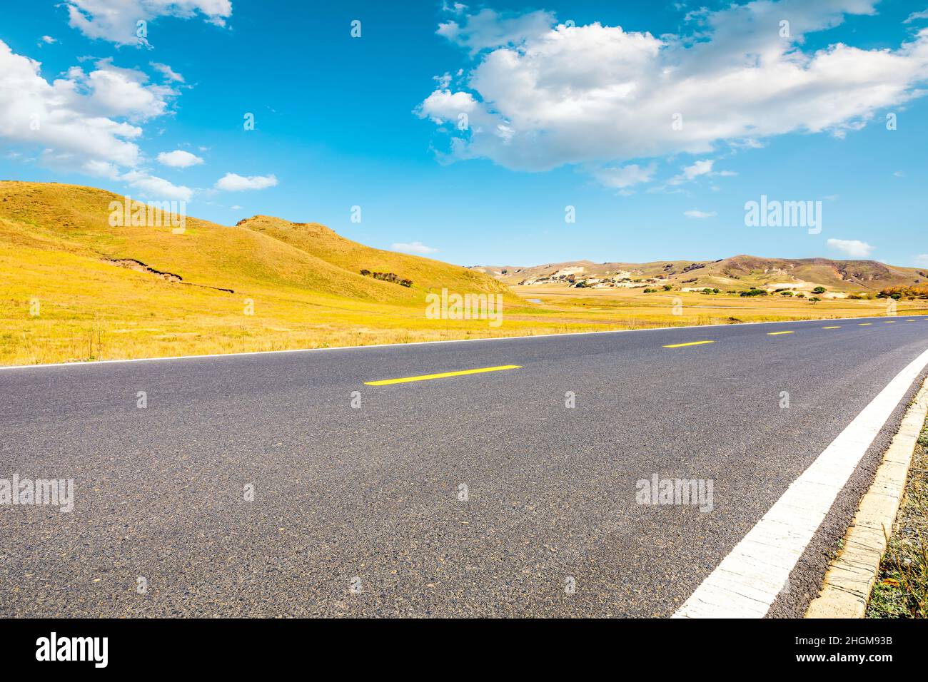 Leere Asphaltstraße und Berglandschaft unter blauem Himmel. Stockfoto