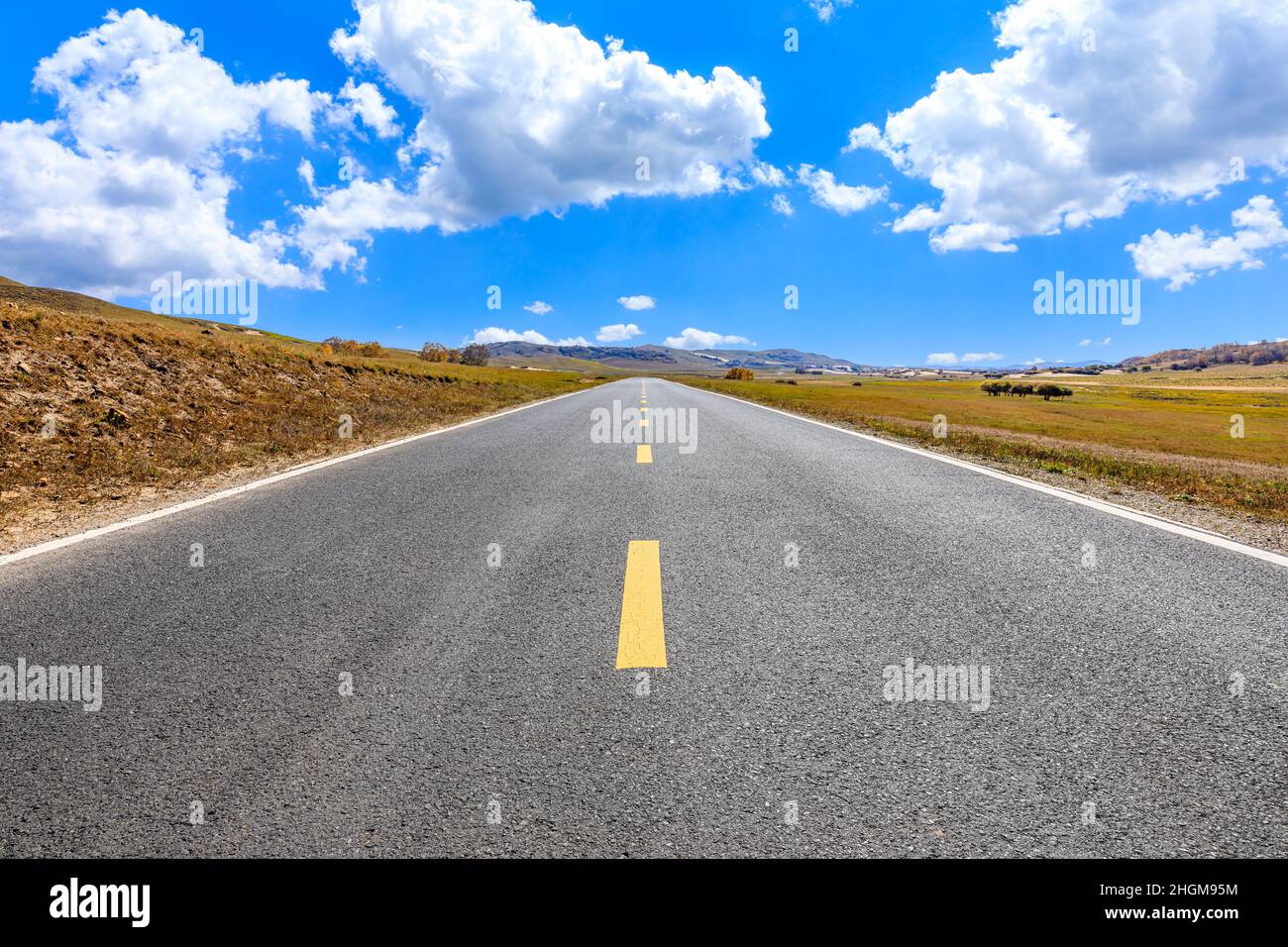 Leere Asphaltstraße und Berglandschaft unter blauem Himmel. Stockfoto