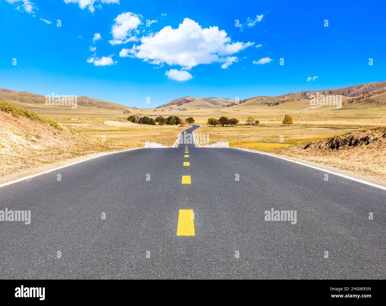 Leere Asphaltstraße und Berglandschaft unter blauem Himmel. Stockfoto