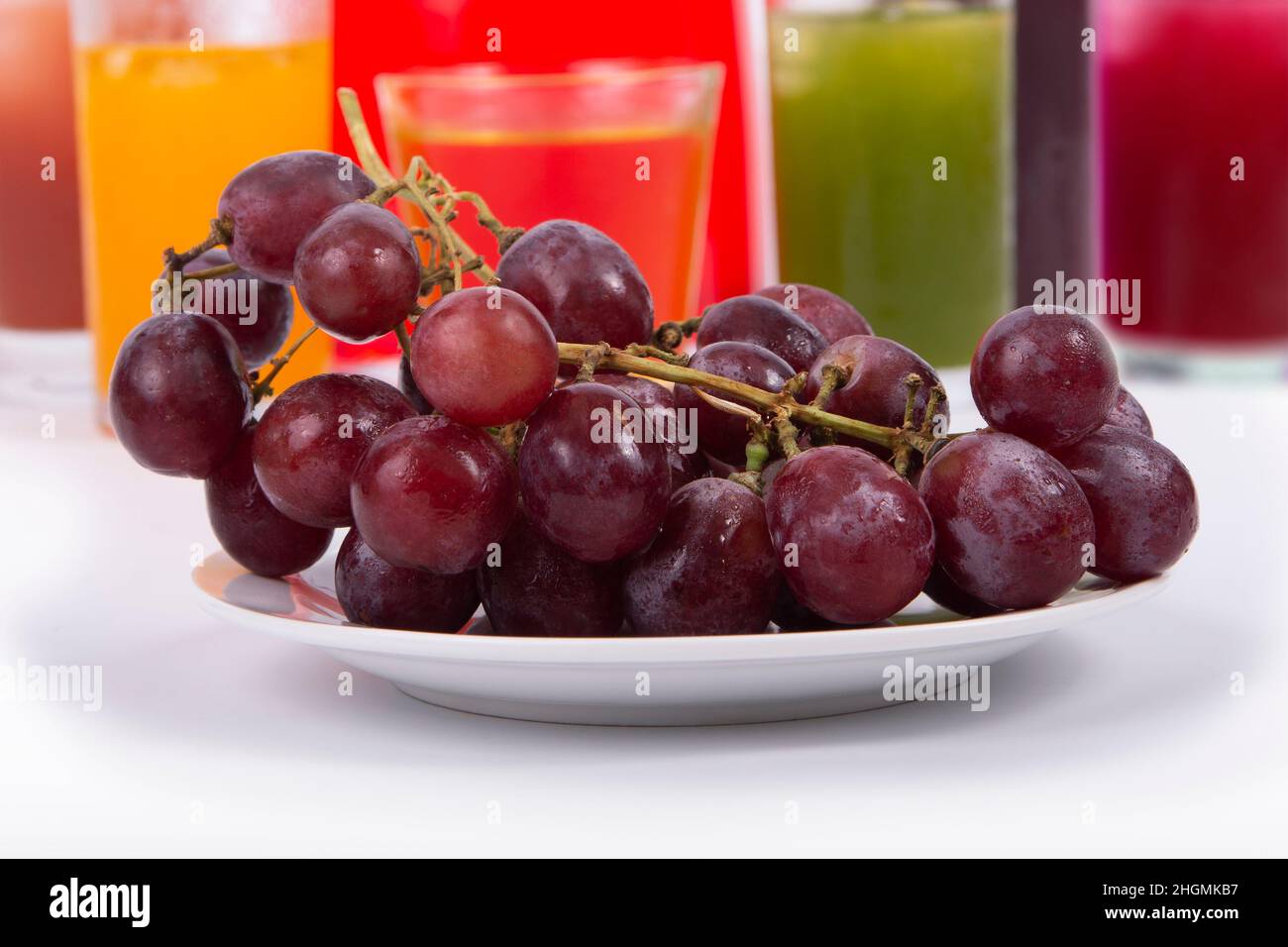 Köstliche frische Trauben mit verschiedenen Glas bunten Säften auf dem Hintergrund. Stockfoto