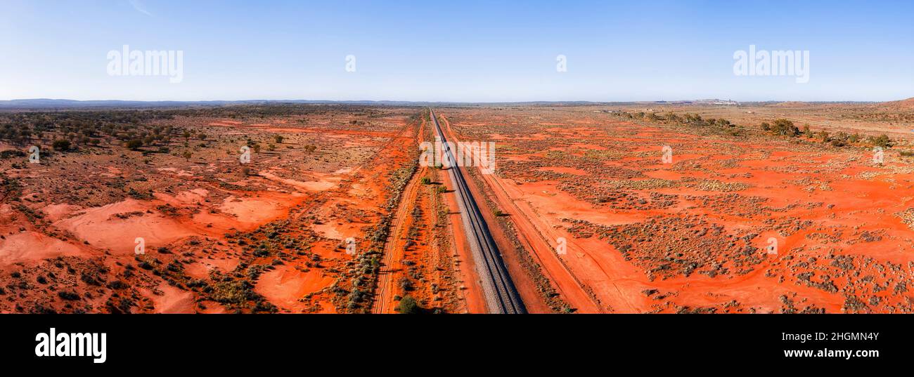 Weite Landschaft mit rotem Boden im Outback in der Nähe von Broken Hill in Australien über die Eisenbahnstrecke und den Barrier Highway. Stockfoto