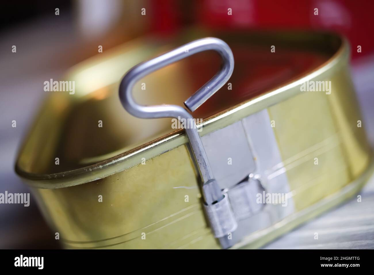 Makro-Nahaufnahme von isoliertem Drehschlüssel Dosenöffner von trinagular-Metalldose auf weißem Holztisch Stockfoto