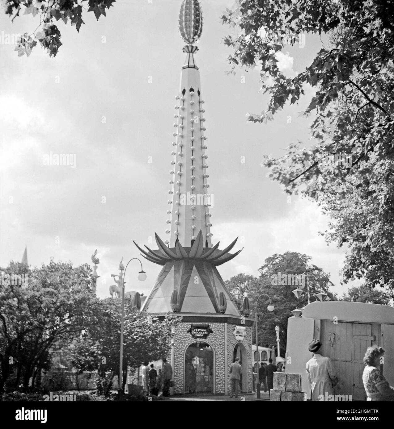 Der beliebte ‘Festival Chocolate Shop’ beim Festival of Britain Pleasure Gardens, Battersea Park, London, England, Großbritannien während der Feierlichkeiten im Jahr 1951. Die Lustgärten waren ein wichtiger Teil des Festivals. Ein sehr dekoratives, lustiges Design ist ein Merkmal des Ladens mit organischen ‘Pflanzen’-Motiven – eine ‘Ananas’ rundet das Gebäude ab. Es ist auch mit Glühbirnen für die Nachtbeleuchtung bedeckt. Dieses Bild stammt aus einem alten Amateur-Schwarz-Weiß-Negativ – einem Vintage-Foto aus dem Jahr 1950s. Stockfoto