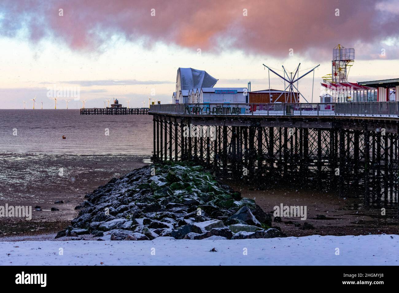 Eine verschneite Szene kurz vor Sonnenuntergang an der Herne Bay mit dem Pier im Vordergrund im Februar 2021. Stockfoto