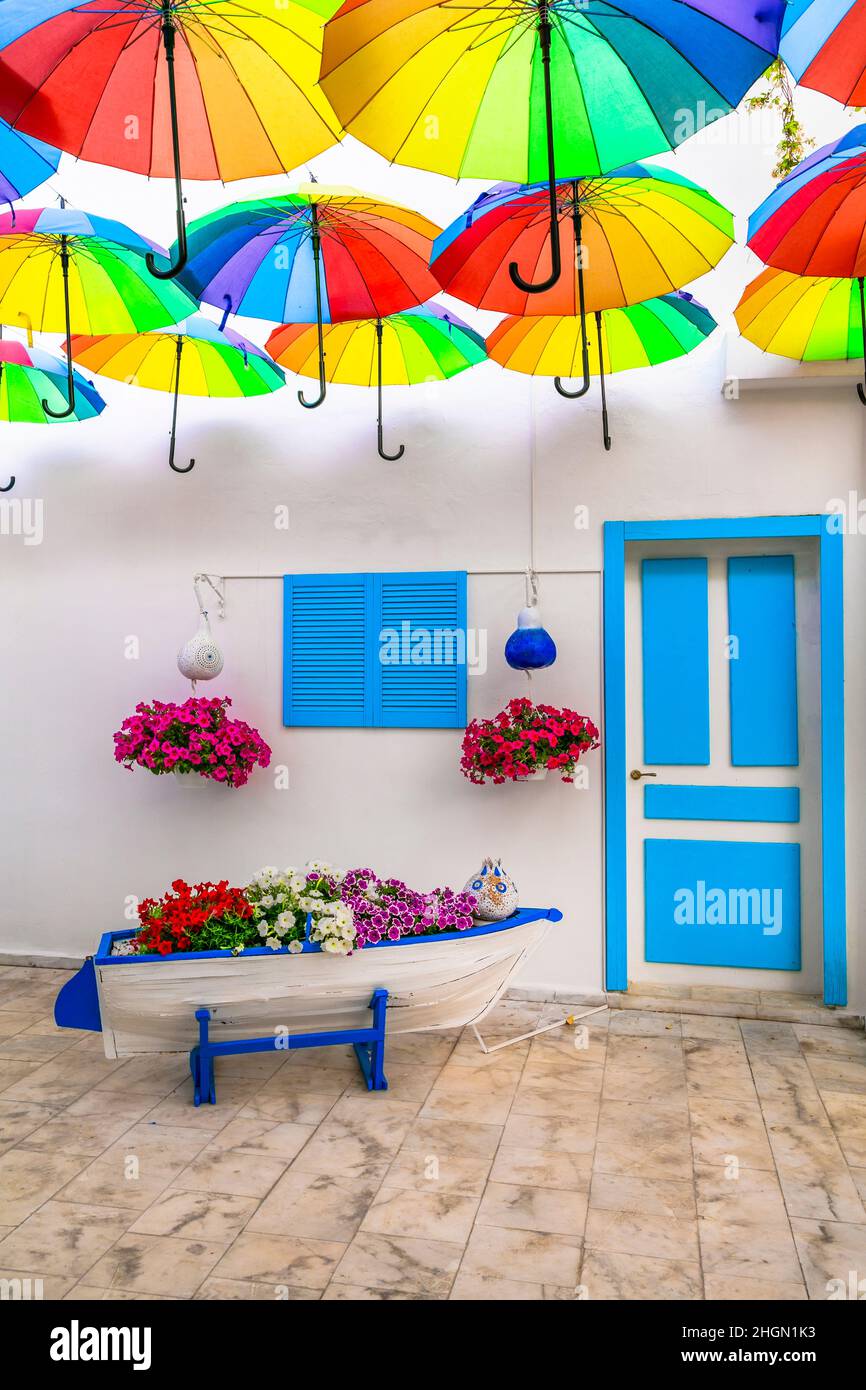 Blumendekoration im Freien mit bunten Regenschirmen. Ideen für Gartengestaltung. mediterrane Einrichtung Stockfoto