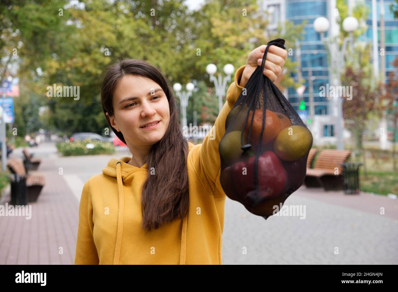 Die Frau zeigt einen schwarzen transparenten Stoffbeutel mit Früchten. Stockfoto