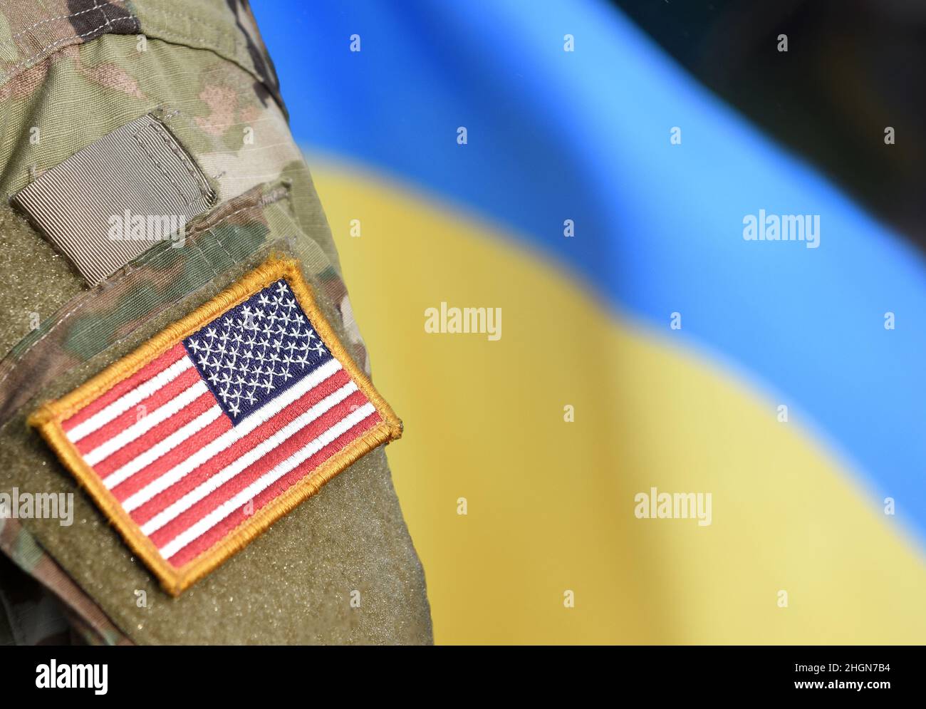 Amerikanische Flagge auf Soldaten Arm und Flagge der Ukraine im Hintergrund. US-Militär unterstützt die Ukraine. Stockfoto