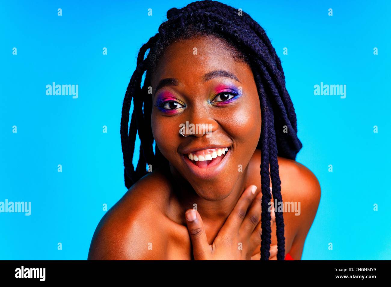 afroamerikanische Frau mit Gorgeus helle Farbe Make-up fühlt sich stolz und selbstbewusst in blauen Wand Studio Hintergrund Stockfoto