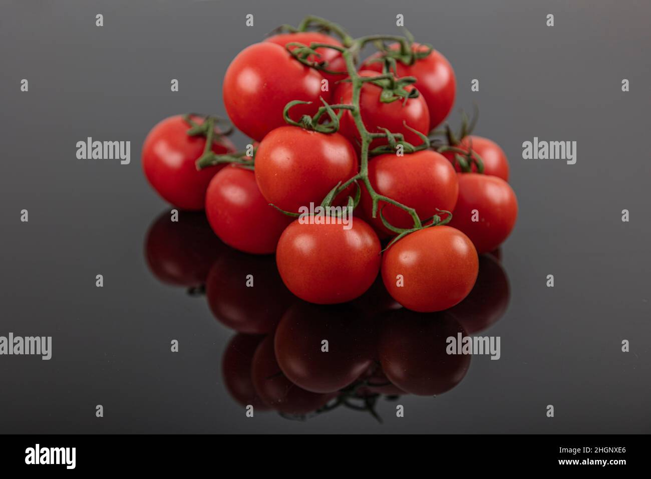 Schöne frische Weintomaten (Kirsche) mit Tropfen Wasser, roh, ganz und halbiert. Auf schwarzem texturierten Schieferhintergrund. Zutaten des Mediterranea Stockfoto