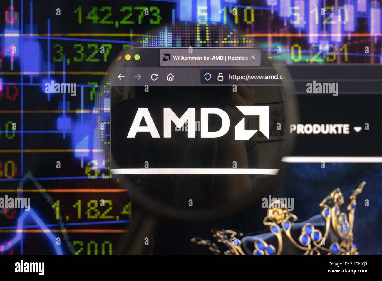 AMD-Firmenlogo auf einer Website mit verschwommenen Börsenentwicklungen im Hintergrund, auf einem Computerbildschirm durch eine Lupe gesehen. Stockfoto