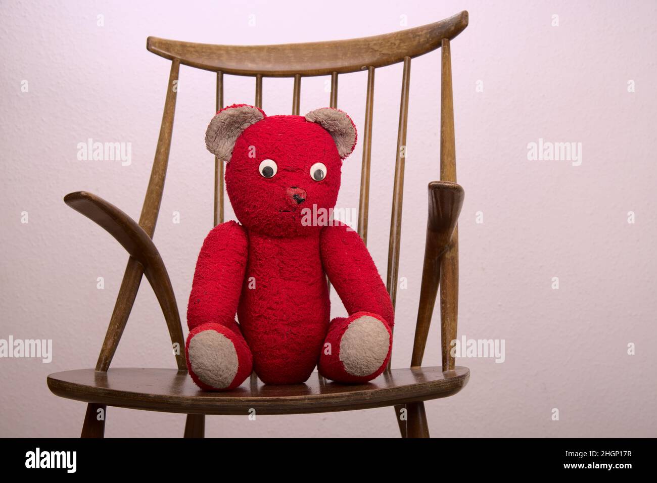 Roter Teddybär auf einem Holzstuhl mit einfachem Hintergrund Stockfoto