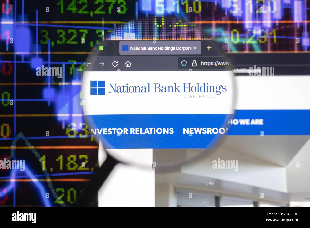 Unternehmenslogo der National Bank Holdings auf einer Website mit verschwommenen Börsenentwicklungen im Hintergrund, die auf einem Computerbildschirm zu sehen sind Stockfoto