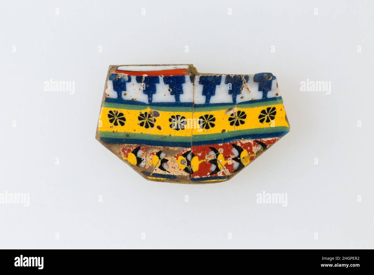 Inlay, Stufenreihe, Rosettenreihe, unklares Muster 100 v. Chr.–100 n. Chr. Ptolemäische Periode–Römische Periode Eine Mosaikglastechnik ermöglichte die Schaffung von Vielfachen eines Bildes: Eine figürliche oder gestalterische Komposition wurde durch Bündelung von farbigen Glasstöcken hergestellt, die dann zu einem langen Balken herausgezogen wurden. Die Stange wurde dann im rechten Winkel geschnitten, wahrscheinlich durch Aufschlagen der Stange mit geeigneten Werkzeugen, um kleine Inlay-Fliesen zu produzieren. Die Fliese würde dann geglättet und auf dem Gesicht poliert, das nach außen erscheinen soll.solche Elemente könnten auch nebeneinander verwendet werden, um sich wiederholende Muster zu erstellen. Oder wenn die Stange prese Stockfoto