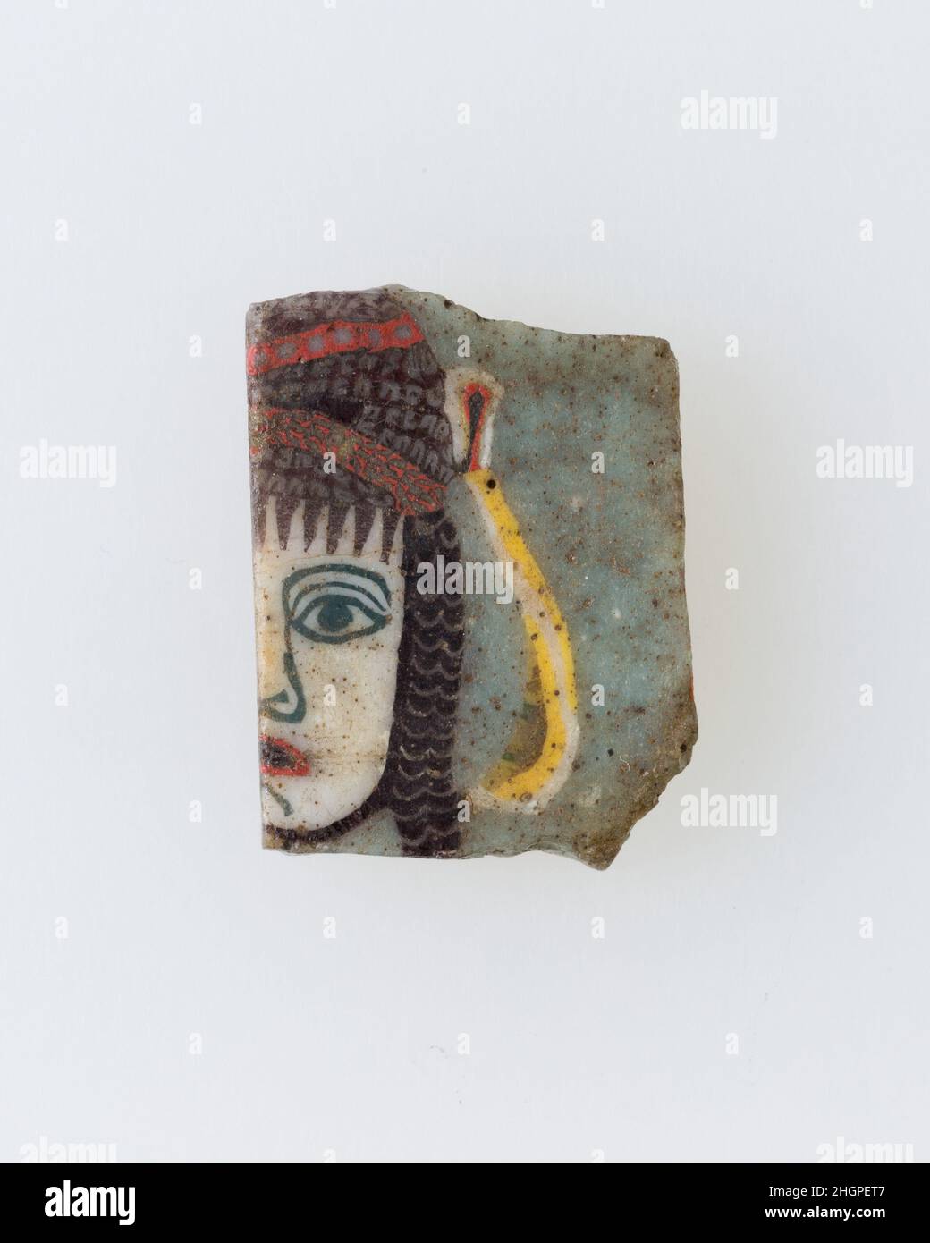 Einlage, weibliches Gesicht 100 v. Chr.–100 n. Chr. Ptolemäische Periode–Römische Zeit Eine Mosaikglastechnik ermöglichte die Schaffung von Vielfachen eines Bildes: Eine figürliche oder gestalterische Komposition wurde durch Bündelung von farbigen Glasstöcken hergestellt, die dann zu einem langen Balken herausgezogen wurden. Die Stange wurde dann im rechten Winkel geschnitten, wahrscheinlich durch Aufschlagen der Stange mit geeigneten Werkzeugen, um kleine Inlay-Fliesen zu produzieren. Die Fliese würde dann geglättet und auf dem Gesicht poliert, das nach außen erscheinen soll.solche Elemente könnten auch nebeneinander verwendet werden, um sich wiederholende Muster zu erstellen. Oder wenn der Stab eine Hälfte eines Elements darstellte, das symmetrisch war Stockfoto