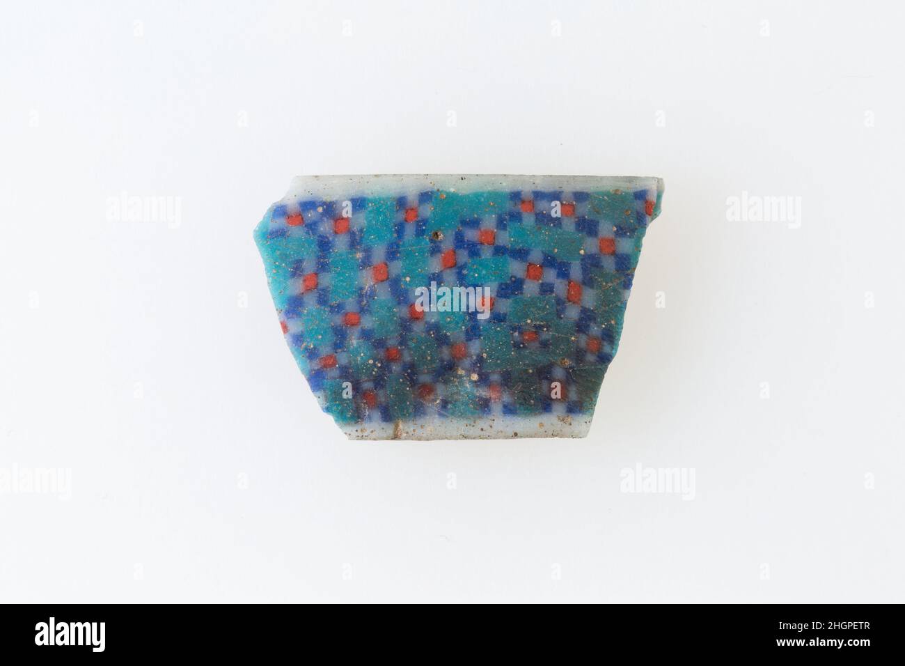 Inlay-Fragment, patten aus Diamanten, die aus kleineren Quadraten gebildet wurden 100 v. Chr.–100 n. Chr. Ptolemäische Periode–Römische Periode Eine Mosaikglastechnik ermöglichte die Erstellung von Vielfachen eines Bildes: Eine figürliche oder gestalterische Komposition wurde durch Bündelung von farbigen Glasstöcken hergestellt, die dann zu einem langen Balken herausgezogen wurden. Die Stange wurde dann im rechten Winkel geschnitten, wahrscheinlich durch Aufschlagen der Stange mit geeigneten Werkzeugen, um kleine Inlay-Fliesen zu produzieren. Die Fliese würde dann geglättet und auf dem Gesicht poliert, das nach außen erscheinen soll. Inlay-Fragment, patten aus Diamanten, die aus kleineren Quadraten gebildet werden. 100 V. CHR.–100 N. CHR. Glas. Ptolem Stockfoto