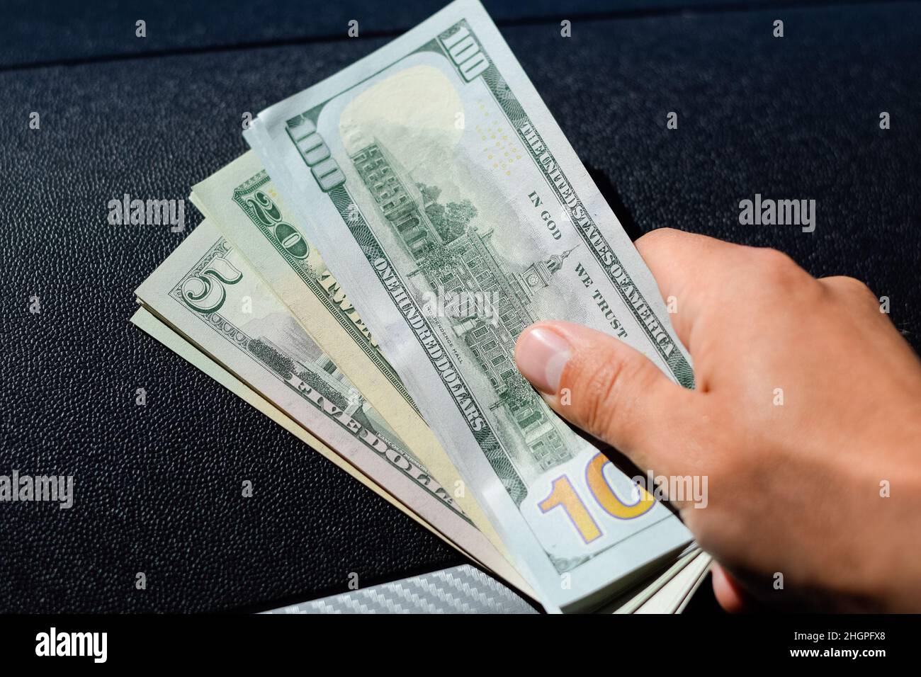 Ein Mann übergibt Geld in einem Auto. Eine Wadel Dollar in seiner Hand. Stockfoto