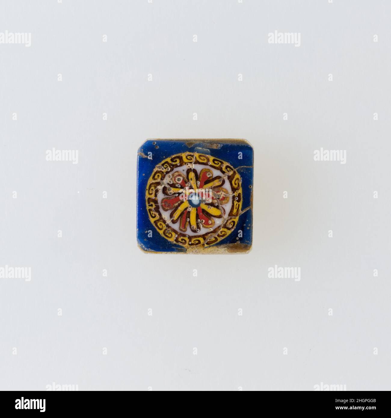 Inlay, Rosette 100 v. Chr.–100 n. Chr. Ptolemäische Periode–Römische Zeit Eine Mosaikglastechnik ermöglichte die Erstellung von Vielfachen eines Bildes: Eine figürliche oder gestalterische Komposition wurde durch Bündelung von farbigen Glasstöcken hergestellt, die dann zu einem langen Balken herausgezogen wurden. Die Stange wurde dann im rechten Winkel geschnitten, wahrscheinlich durch Aufschlagen der Stange mit geeigneten Werkzeugen, um kleine Inlay-Fliesen zu produzieren. Die Fliese würde dann geglättet und auf dem Gesicht poliert, das nach außen erscheinen soll. Inlay, Rosette. 100 V. CHR.–100 N. CHR. Glas. Ptolemäische Periode–Römische Periode. Aus Ägypten Stockfoto