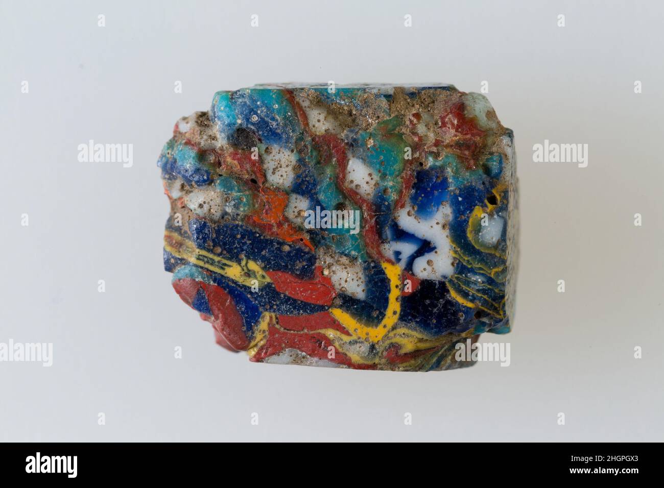 Inlay-Fragment 100 v. Chr.–100 n. Chr. Ptolemäische Periode–Römische Zeit Eine Mosaikglastechnik ermöglichte die Erstellung von Vielfachen eines Bildes: Eine figürliche oder gestalterische Komposition wurde durch Bündelung von farbigen Glasstöcken hergestellt, die dann zu einem langen Balken herausgezogen wurden. Die Stange wurde dann im rechten Winkel geschnitten, wahrscheinlich durch Aufschlagen der Stange mit geeigneten Werkzeugen, um kleine Inlay-Fliesen zu produzieren. Die Fliese würde dann geglättet und auf dem Gesicht poliert, das nach außen erscheinen soll. Inlay-Fragment. 100 V. CHR.–100 N. CHR. Polychromglas. Ptolemäische Periode–Römische Periode. Aus Ägypten, Oberägypten, Theben Stockfoto