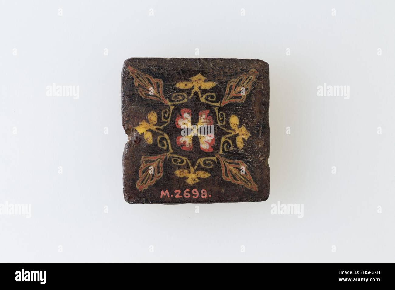 Inlay-Fragment, konventionelles Blumenmuster 1st–3rd Jahrhundert n. Chr. Römische Periode Eine Mosaikglas-Technik ermöglichte die Schaffung von Vielfachen eines Bildes: Eine figürliche oder gestalterische Komposition wurde durch die Bündelung von farbigen Glasstöcken hergestellt, die dann zu einem langen Balken herausgezogen wurden. Die Stange wurde dann im rechten Winkel geschnitten, wahrscheinlich durch Aufschlagen der Stange mit geeigneten Werkzeugen, um kleine Inlay-Fliesen zu produzieren. Die Fliese würde dann geglättet und auf dem Gesicht poliert, das nach außen erscheinen soll. Intarsienfragment, konventionelles Blumenmuster. 1st–3rd Jahrhundert n. Chr. Mosaikglas. Römische Zeit. Aus Ägypten Stockfoto