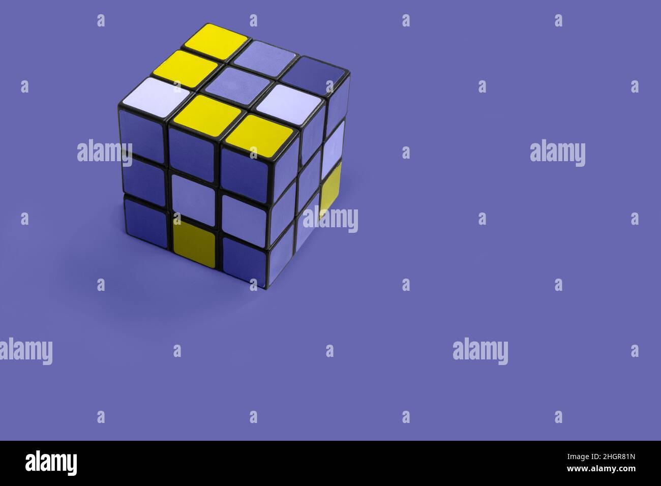 Ein bearbeiteter rubik-Würfel auf einem violetten Hintergrund. Der Würfel ist gelb und lila, einschließlich sehr peri die Pantone-Farbe, wenn das Jahr 2022. Stockfoto