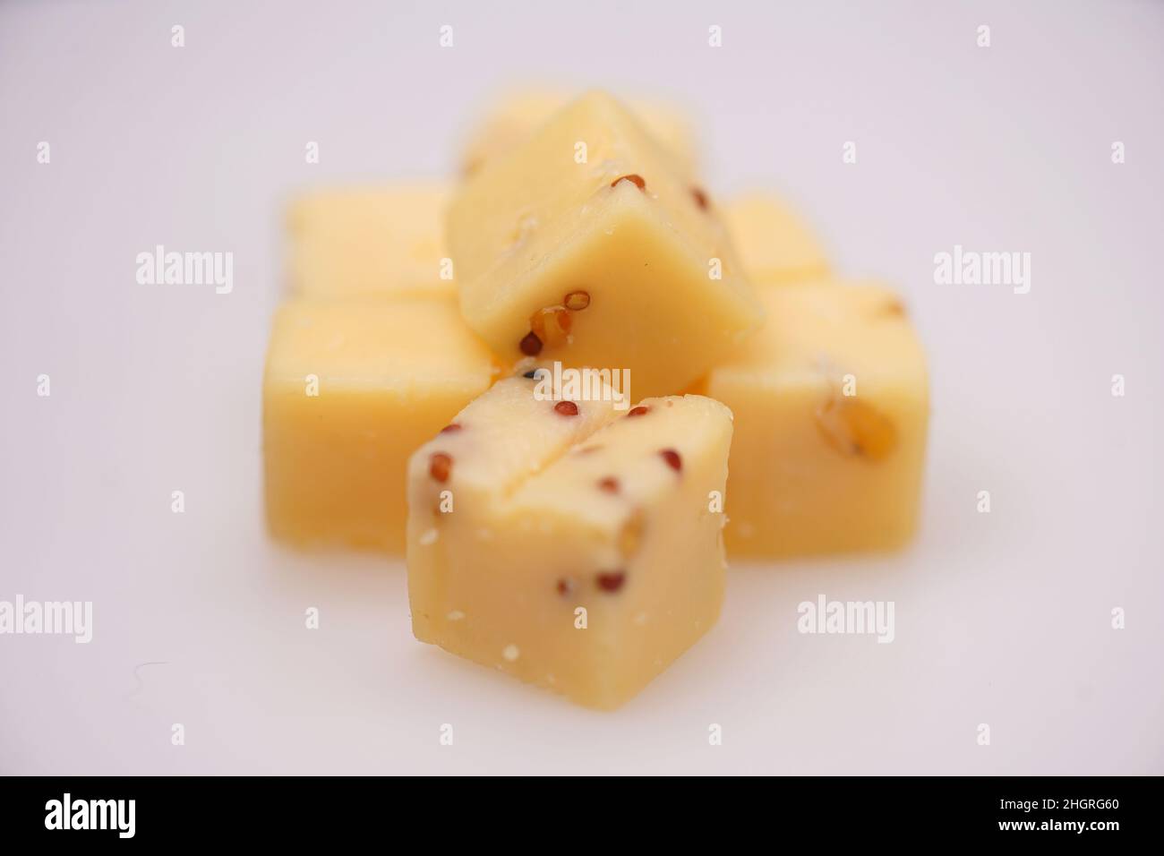 Nahaufnahme von 5 Blöcken für Käse mit Senfkörnern vor weißem Hintergrund Stockfoto