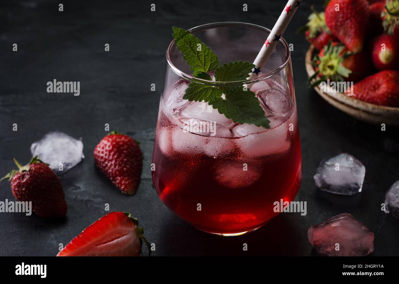 Kalter Cocktail mit Erdbeeren und Eis auf schwarzem Hintergrund. Sommerliche Drinks auf dunkle Art und Weise. Stockfoto