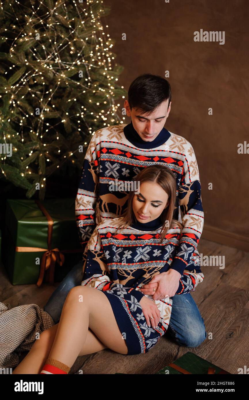 Ein Mann und ein Mädchen umarmen und küssen sich vor dem Hintergrund eines Weihnachtsbaums Stockfoto