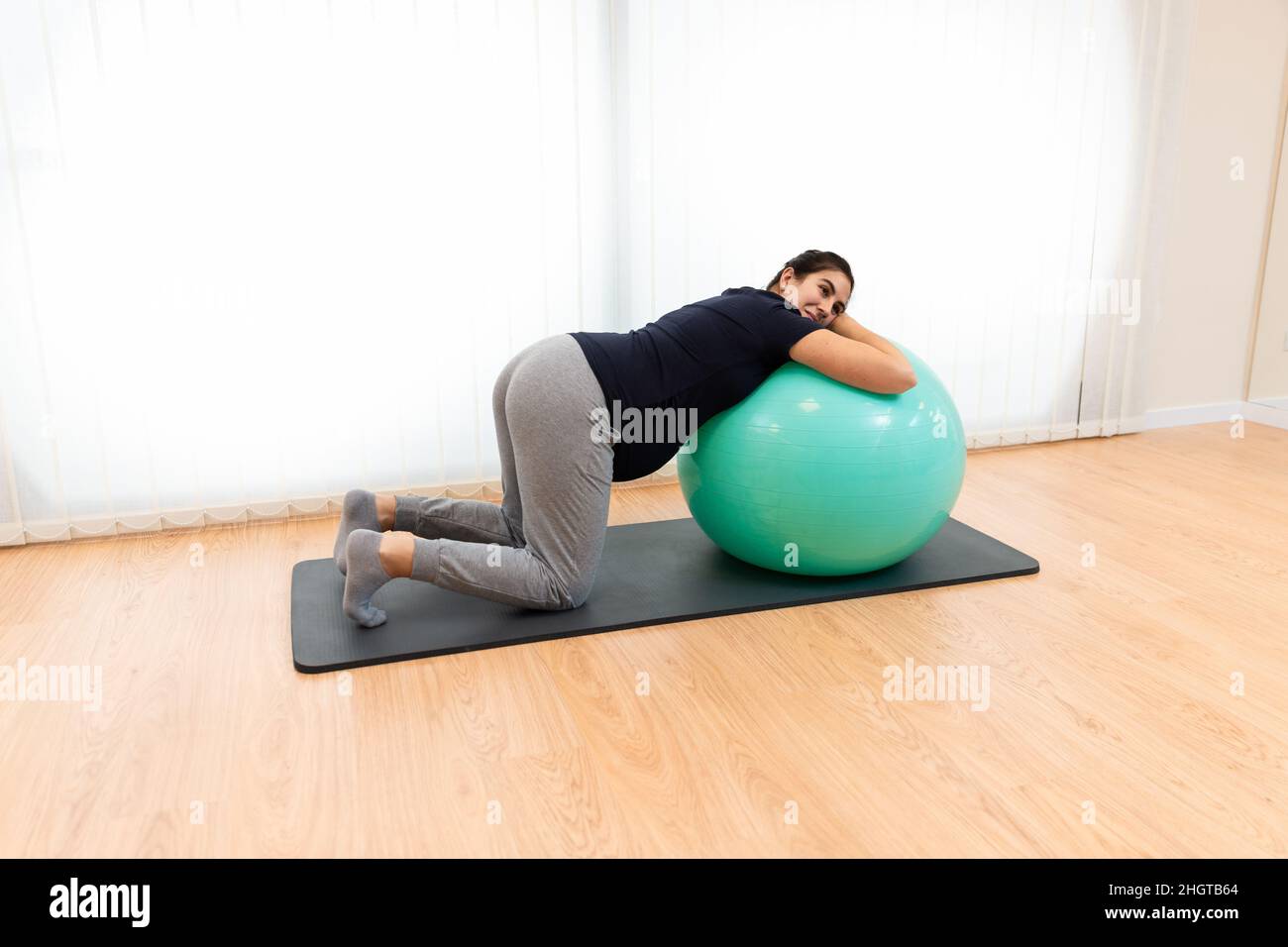 Eine Schwangerin macht Atemübungen und ruht sich auf einem Fitnessball aus Stockfoto