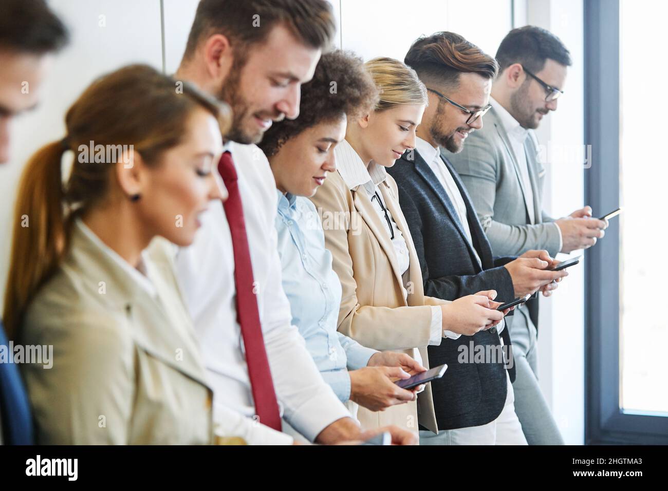 Junge Geschäftsleute arbeiten mit einem Mobiltelefon, einem Smartphone oder einem Social-Media-Gerät zusammen Stockfoto