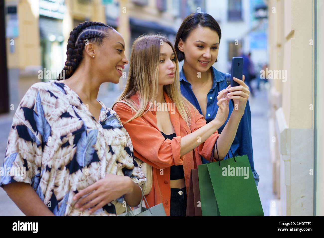 Modische multirassische Damen, die beim Einkaufen in der Stadt Fotos auf dem Smartphone machen Stockfoto