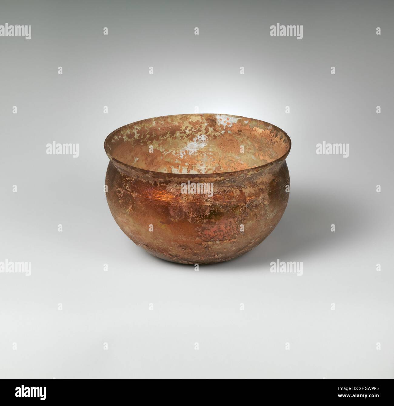 Glasschale 1st. Jahrhundert n. Chr. römisch farblos mit blaugrünem Kribbeln abgeknickter, unebener, senkrechter Rand; kurzer konkaver Hals; konvexe Seiten, die in den konkaven Boden eingebogen sind.Verzierung von vier parallelen Bändern mit radabgeschliffenen Linien am Körper, die zum Rand hin abfallen.intakt, bis auf einen sehr kleinen Chip im Rand; viele Nadelstachelblasen; Tiefes Lochfraß, Abstumpfen und schillernde Verwitterung an der Außenseite; cremebraune Verwitterung an der Innenseite. Glasschale. Roman. 1st Jahrhundert n. Chr.. Glas; geblasen und geschnitten. Frühkaiserlich. Glas Stockfoto