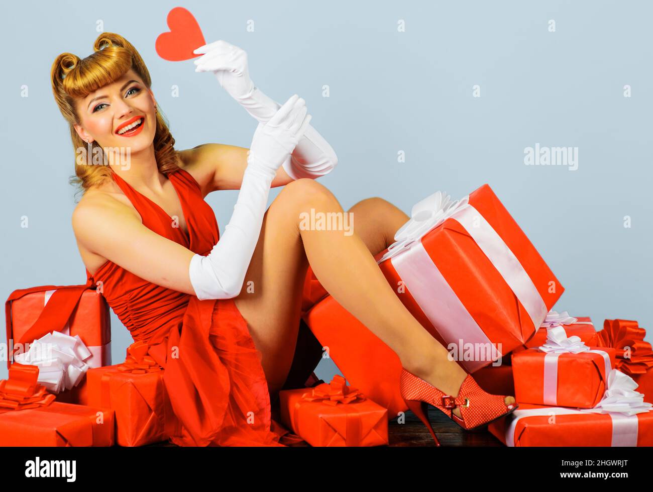 Valentinstag. Frau mit rotem Herzen. Februar 14. Liebe. Lächelndes Mädchen in rotem Kleid mit Geschenk-Box. Stockfoto