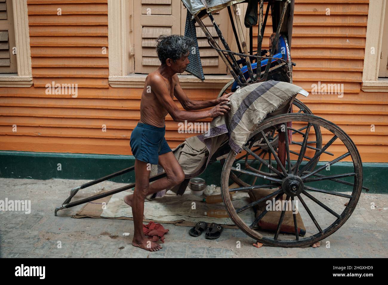 Eine gezogene Rikscha, ein Transportmodus, bei dem ein Läufer einen zweirädrigen Wagen zieht, in dem ein oder zwei Personen Platz finden. Kalkutta, Indien Stockfoto