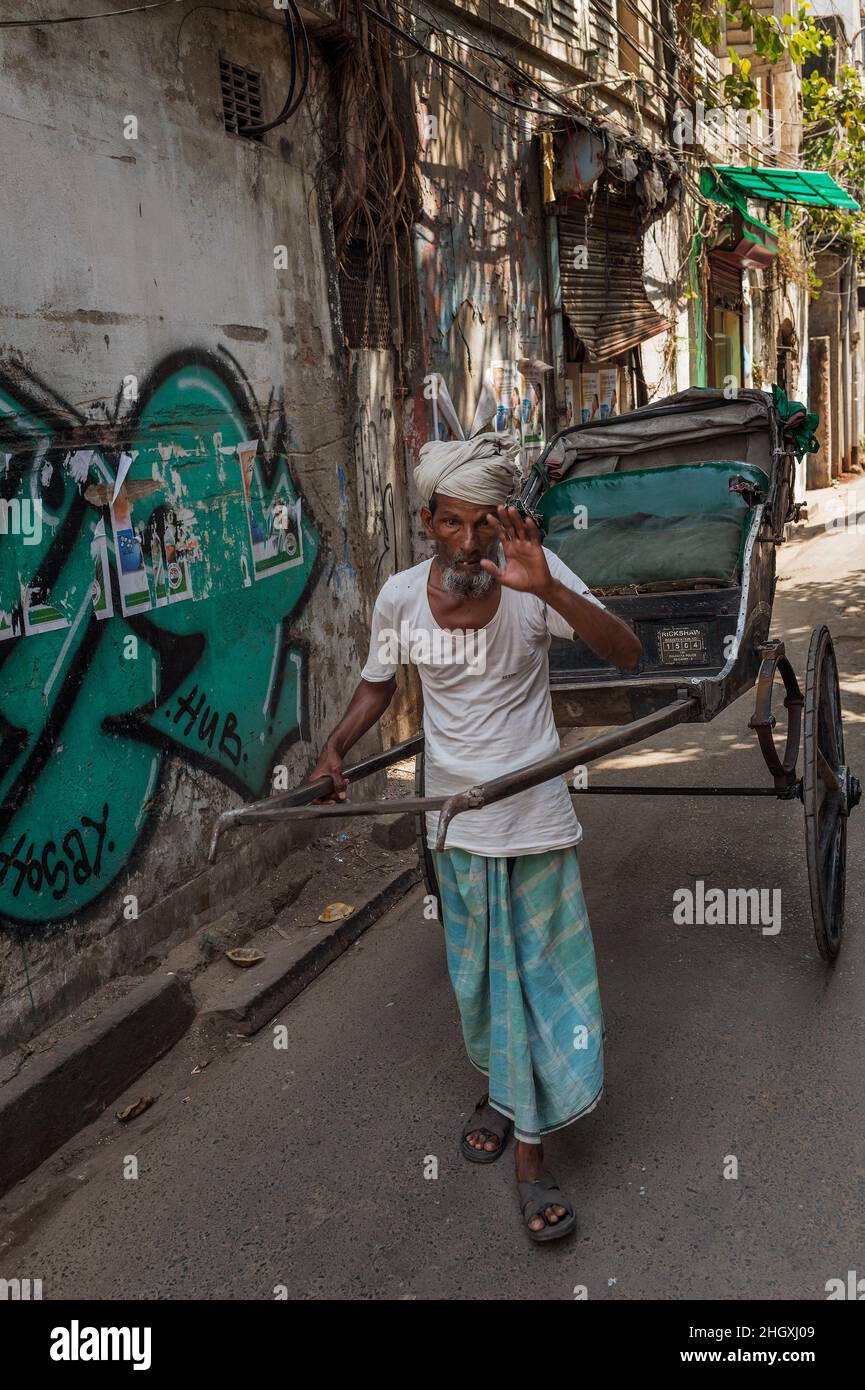 Eine gezogene Rikscha, ein Transportmodus, bei dem ein Läufer einen zweirädrigen Wagen zieht, in dem ein oder zwei Personen Platz finden. Kalkutta, Indien Stockfoto