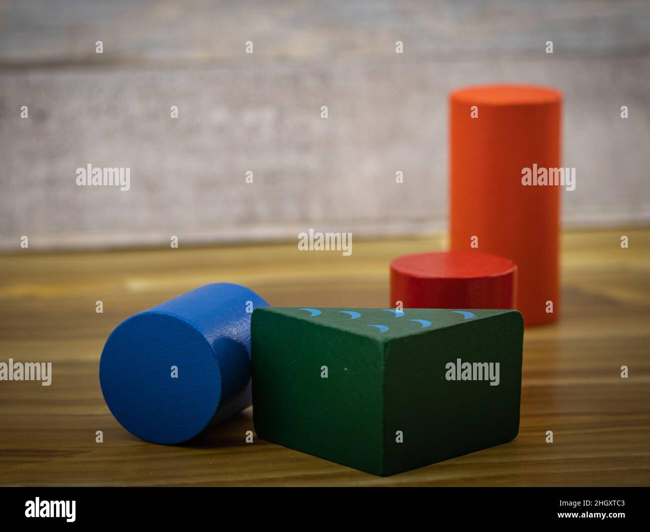 Bunte Holzspielblöcke, einschließlich Zylinder und rechteckige Prismen, auf einer Holzfläche platziert. Ideal für die Illustration von Bildung, Lernen und Spielereien Stockfoto