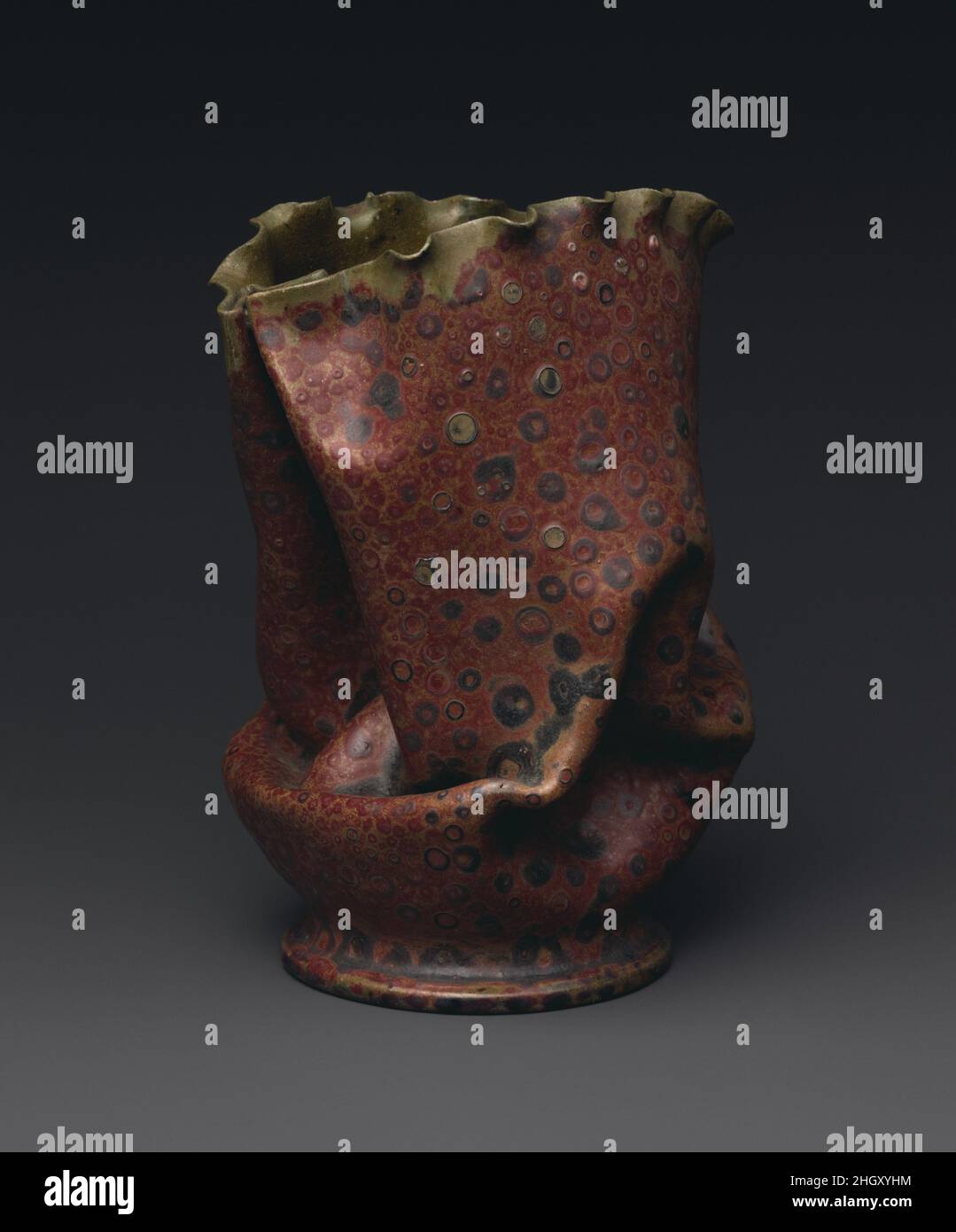Vase ca. 1897-1900 George E. Ohr George Ohr aus Biloxi, Mississippi, war wohl Amerikas Quintessenz-Kunsttöpfer. Er baute seinen eigenen Ofen, grub seinen Ton aus, warf seine Gefäße mit extremer Kompetenz auf das Töpferrad bis zu hauchdünn, veränderte diese Formen und bedeckte sie dann mit seinen eigenen neuartigen Glasuren. In Form und Dekoration sind sie im Wesentlichen abstrakte expressionistische Objekte – fast 50 Jahre vor der Gründung dieser Bewegung. In der Tat, die in diesem Jahrhundert als sehr modern galten, hatten sie großen Anklang an moderne Künstler wie Jasper Johns und Andy Warhol, die Sammlungen von ihnen bildeten. Stockfoto