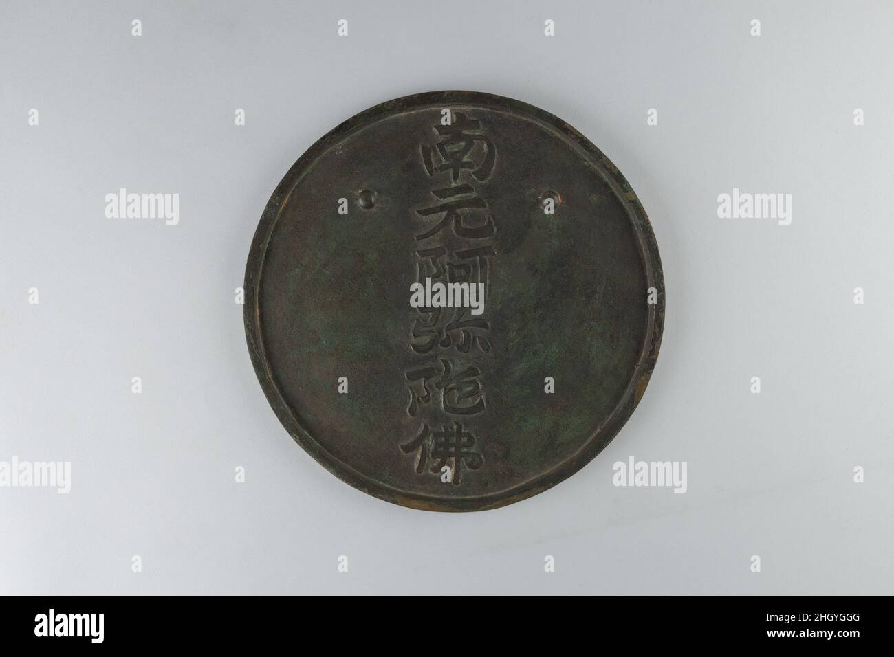 Magischer Spiegel mit dem Bild des Buddha Amida 19th. Jahrhundert Japan dieser Spiegel, eine buddhistische Ikone, verbirgt ein Bild des Buddha Amida (Sanskrit: Amit?bha), das 48 Lichtstrahlen ausstrahlt, einen für jedes der Gelübde, die er als Bodhisattva abgelegt hat. Das Bild wird nur unter besonderen Lichtbedingungen sichtbar. Die Rückseite des Spiegels trägt den sechsstelligen Satz „Namu Amida Butsu“ (Hagel the Name of Amida Buddha). Spiegel dieser Art werden „magische Spiegel“ oder „maky“ genannt? Auf Japanisch. Hergestellt in China von sehr früh an, wurden sie auch in Japan für religiöse und weltliche Verwendung populär. Magic Mirror mit Stockfoto