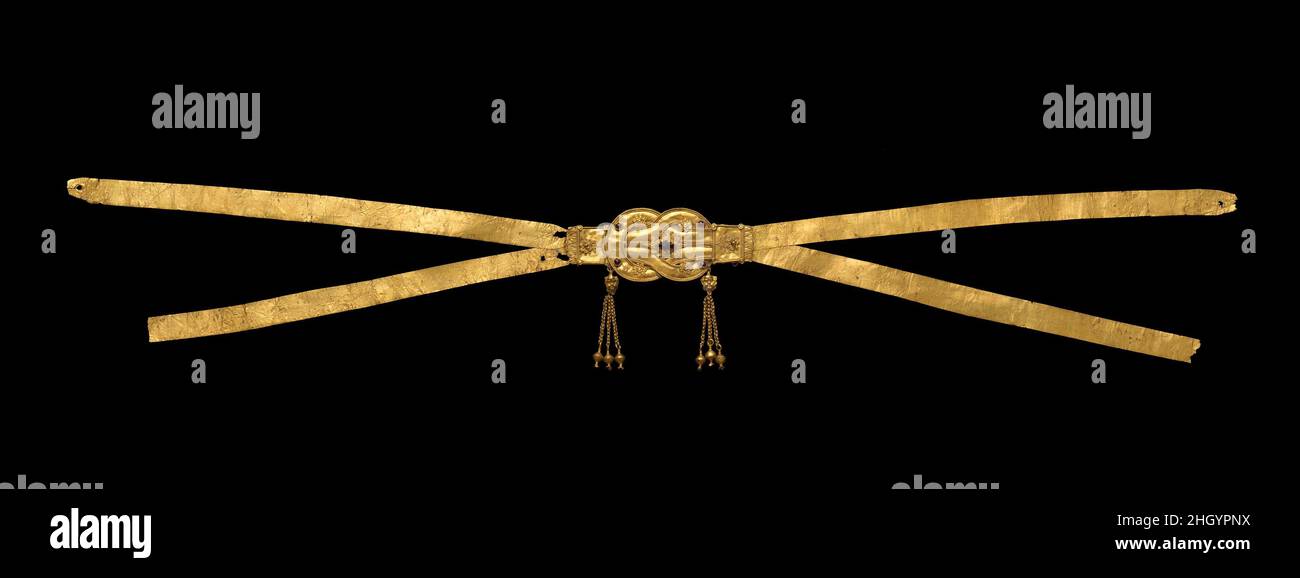 Goldfarbenes Kreuzband-Diadem mit einem Herakles-Knoten mit fünf Granaten ca. 300–250 v. Chr. Griechisch sowohl das Diadem als auch der angrenzende Ring wurden in einem Grab der Insel Ithaka gefunden. Goldfarbenes Kreuzband-Diadem mit einem Herakles-Knoten mit fünf Granaten. Griechisch. Ca. 300–250 V. CHR. Gold, Granat. Hellenistisch. Gold und Silber Stockfoto