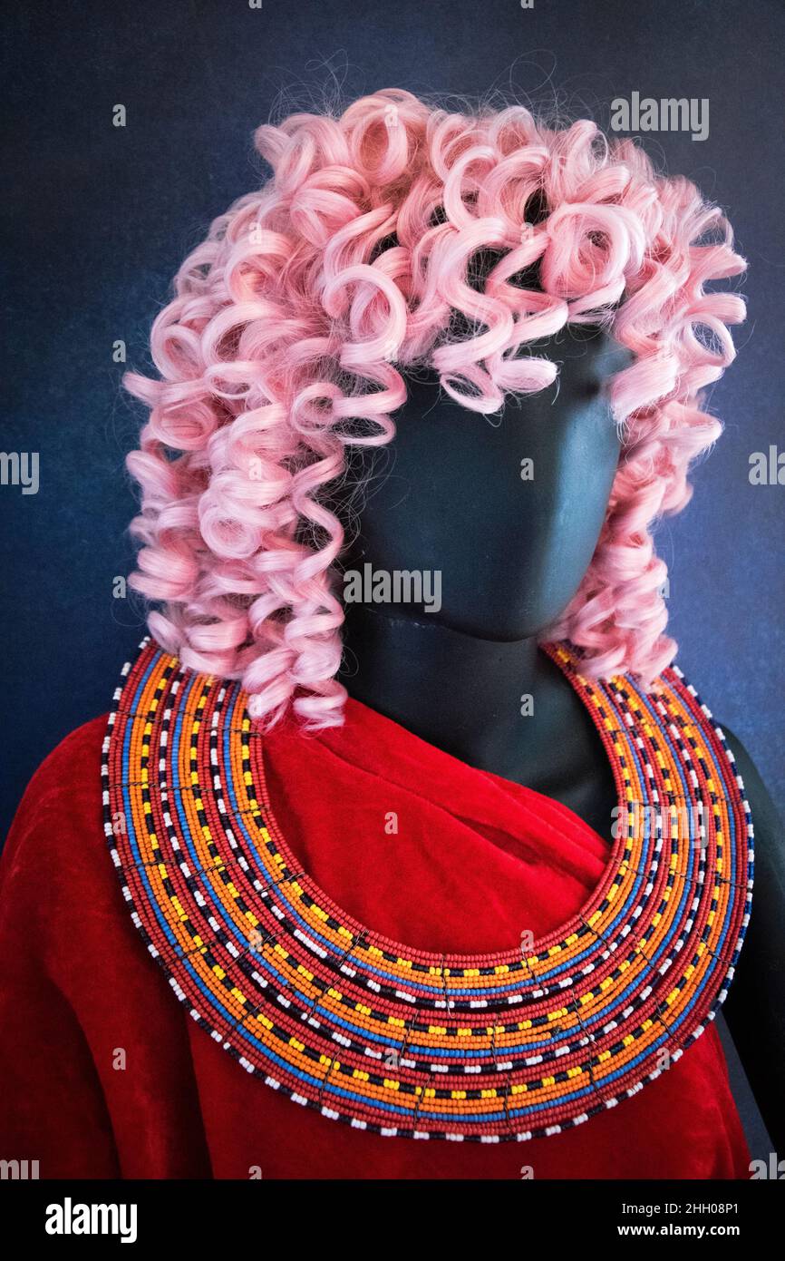 Schaufensterpuppe mit rosafarbenem Haar, tieflesender Kleidung und einer Maasai-Perlenkette. Stockfoto