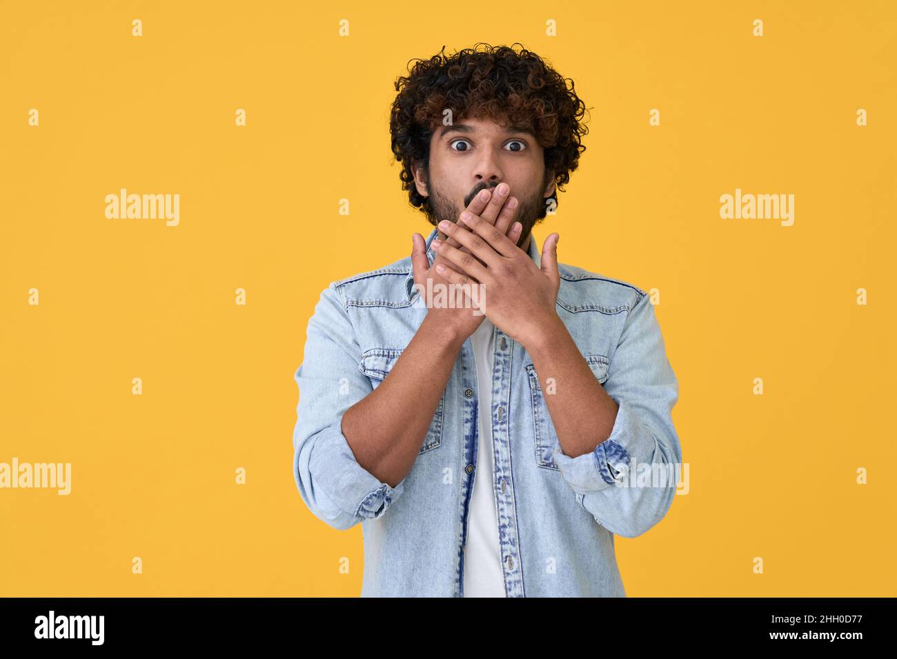 Schockiert überraschte junge indische Mann auf gelbem Hintergrund isoliert. Stockfoto