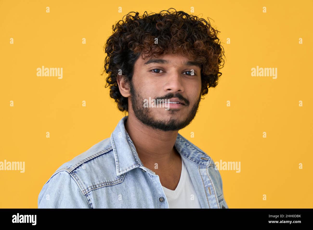 Junger indischer Kerl isoliert auf gelbem Hintergrund, Kopfschuss Nahaufnahme Porträt. Stockfoto