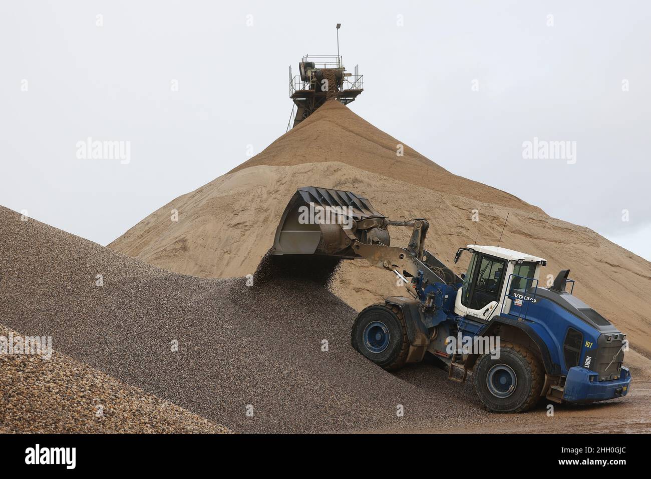 Weeze, Deutschland. 20th Januar 2022. Ein Bagger schaufelt Kies auf einen Vorrat der Kiesfabrik Weeze Kies GmbH & Co.KG der Hülskens Holding. Die Schotterindustrie braucht dringend lokale Rohstoffe, Bauern im Niederrhein fürchten um ihr Land. (An dpa: 'Streit um Niederrheinschotter geht weiter - Planvorlage beginnt am Montag') Quelle: Oliver Berg/dpa/Alamy Live News Stockfoto